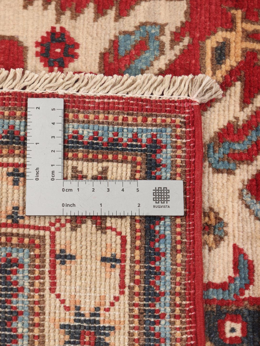 Een handgeknoopt Afghaans Kazak tapijt met gedurfde geometrische rode, blauwe en crèmekleurige motieven.