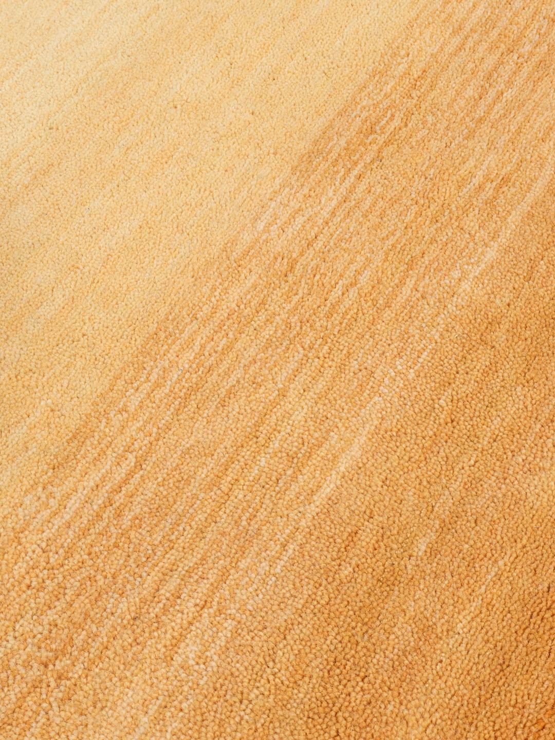 Een rechthoekig handgeweven vloerkleed in verschillende tinten oranje.
