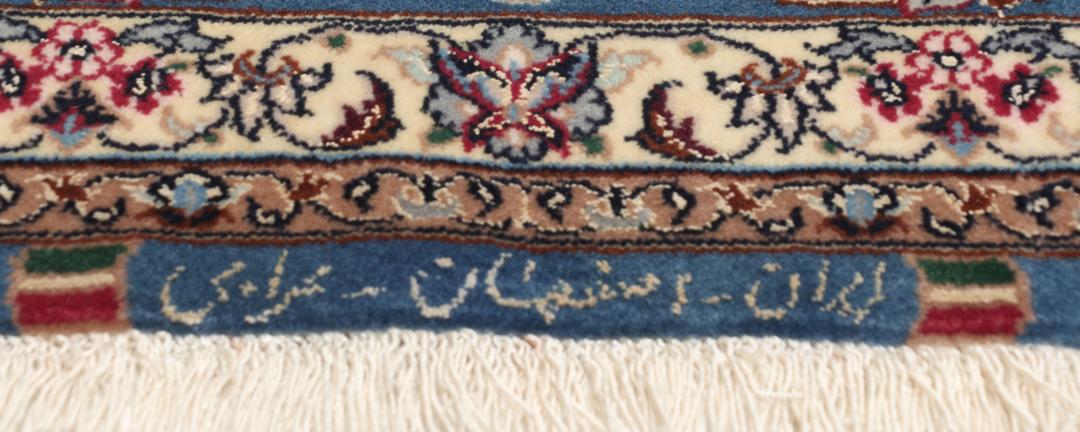 Håndknyttet Isfahan-tæppe med rød bund og indviklede blå og beige blomstermønstre.