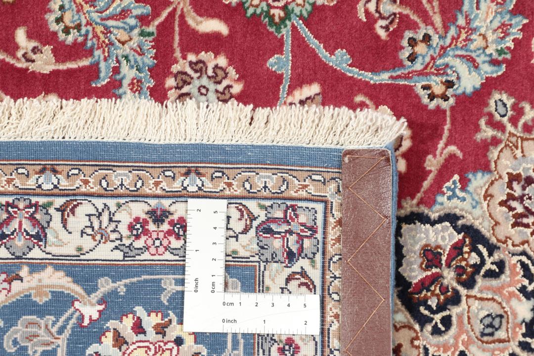 Håndknyttet Isfahan-tæppe med rød bund og indviklede blå og beige blomstermønstre.