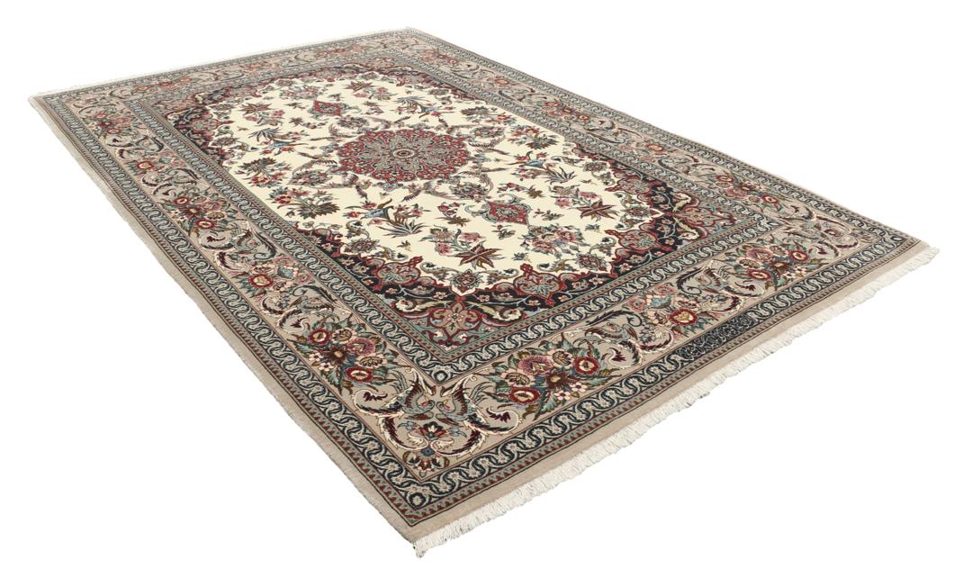Een rechthoekig Isfahan-tapijt uit het Midden-Oosten met een centraal medaillon en bloemmotieven in beige, rode en blauwe tinten.