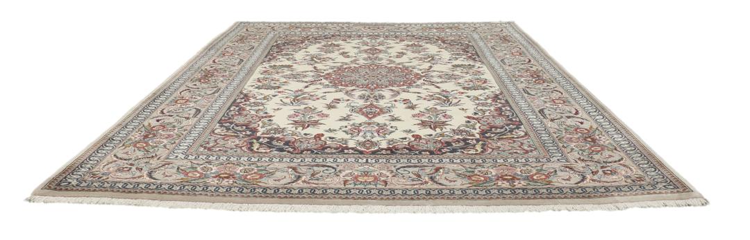 Een rechthoekig Isfahan-tapijt uit het Midden-Oosten met een centraal medaillon en bloemmotieven in beige, rode en blauwe tinten.