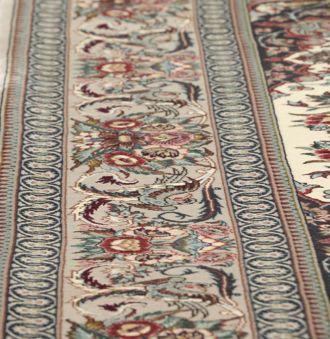 Een rechthoekig Isfahan-tapijt uit het Midden-Oosten met een centraal medaillon en bloemmotieven in beige, rode en blauwe tinten.
