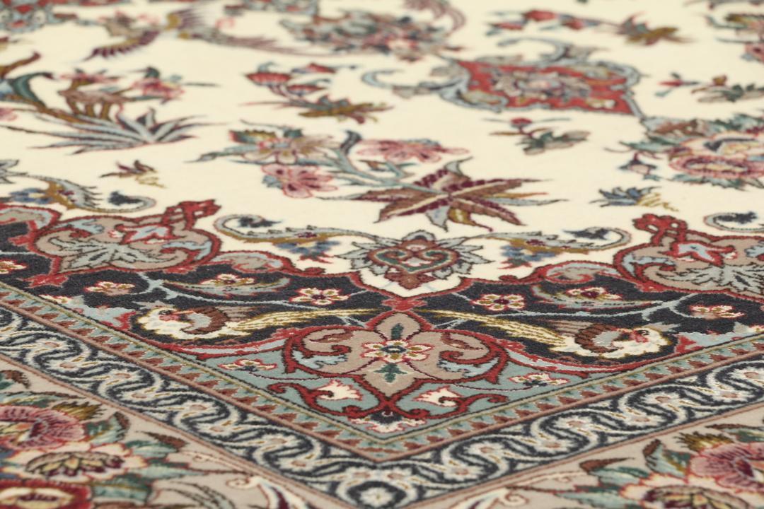 Een rechthoekig Isfahan-tapijt uit het Midden-Oosten met een centraal medaillon en bloemmotieven in beige, rode en blauwe tinten.