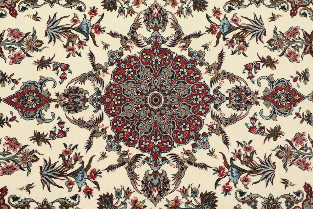 Een rechthoekig Isfahan-tapijt uit het Midden-Oosten met een centraal medaillon en bloemmotieven in beige, rode en blauwe tinten.