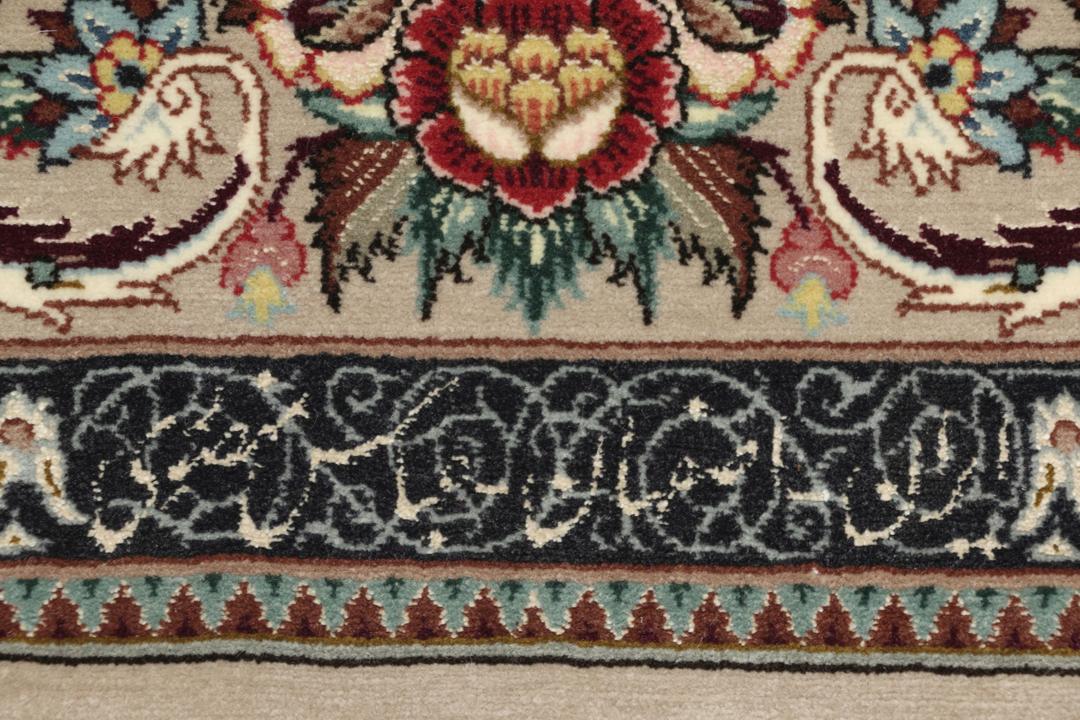 Een rechthoekig Isfahan-tapijt uit het Midden-Oosten met een centraal medaillon en bloemmotieven in beige, rode en blauwe tinten.