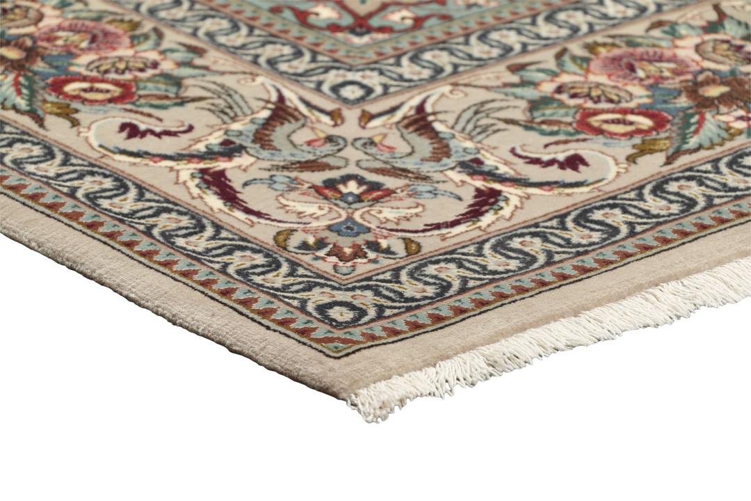 Een rechthoekig Isfahan-tapijt uit het Midden-Oosten met een centraal medaillon en bloemmotieven in beige, rode en blauwe tinten.