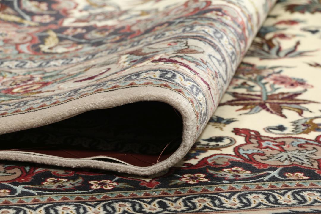 Een rechthoekig Isfahan-tapijt uit het Midden-Oosten met een centraal medaillon en bloemmotieven in beige, rode en blauwe tinten.