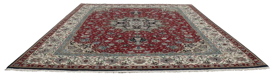 Een handgeknoopt Tabriz-tapijt met een rood veld en een ingewikkeld bloemmedaillon uit het Midden-Oosten.