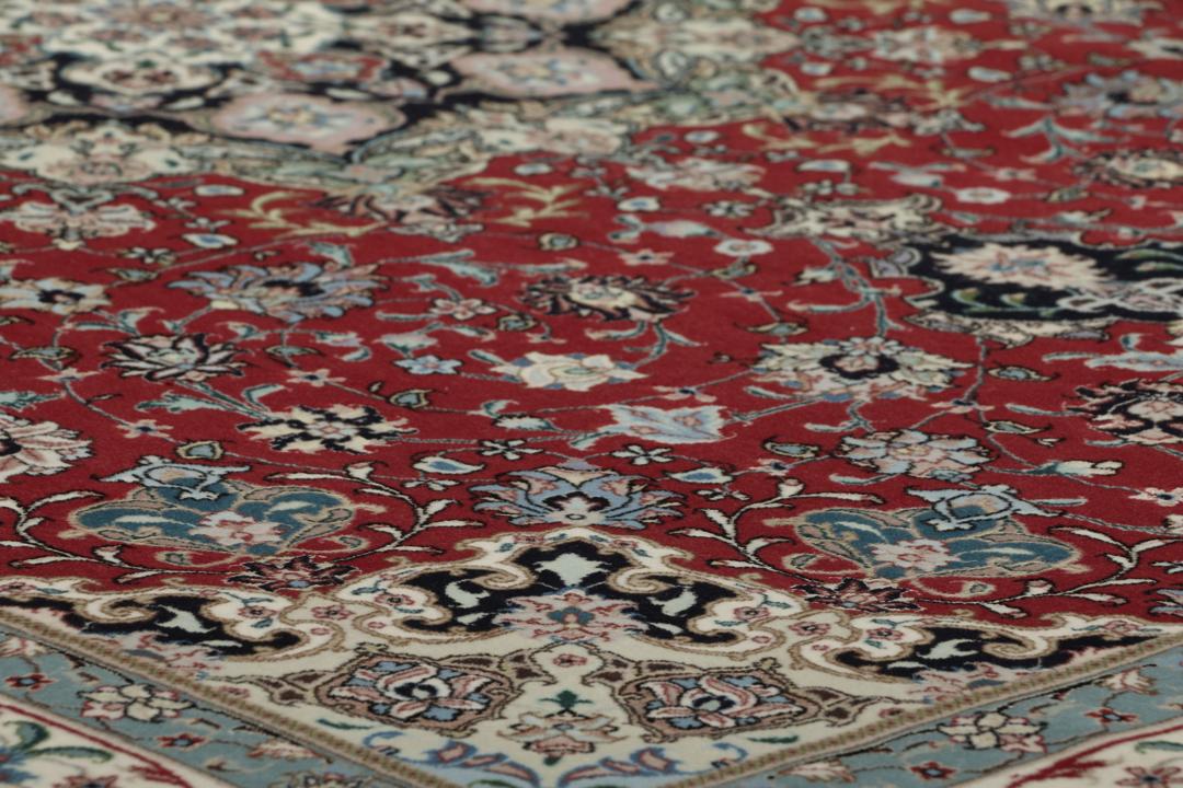 Een handgeknoopt Tabriz-tapijt met een rood veld en een ingewikkeld bloemmedaillon uit het Midden-Oosten.