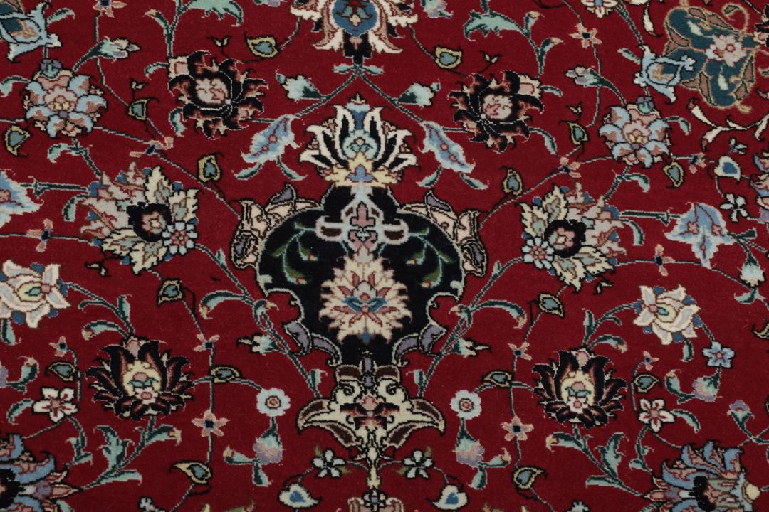 Een handgeknoopt Tabriz-tapijt met een rood veld en een ingewikkeld bloemmedaillon uit het Midden-Oosten.