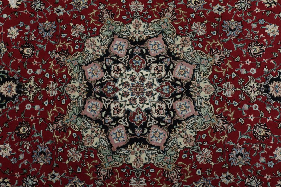Een handgeknoopt Tabriz-tapijt met een rood veld en een ingewikkeld bloemmedaillon uit het Midden-Oosten.