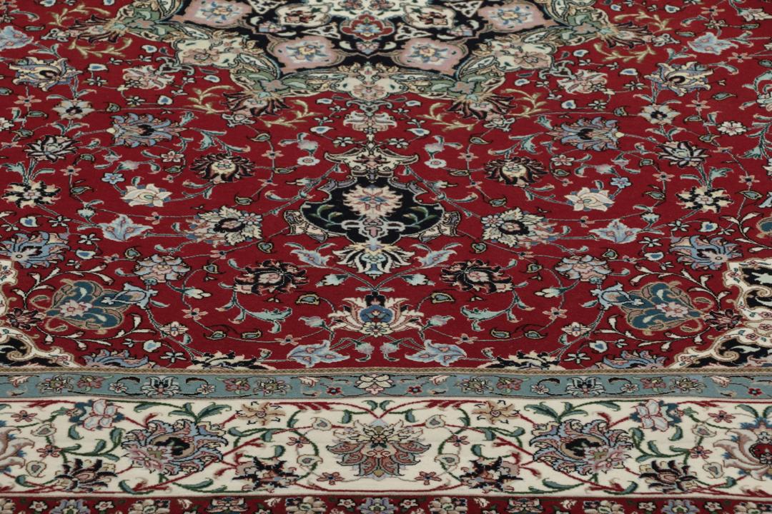 Een handgeknoopt Tabriz-tapijt met een rood veld en een ingewikkeld bloemmedaillon uit het Midden-Oosten.