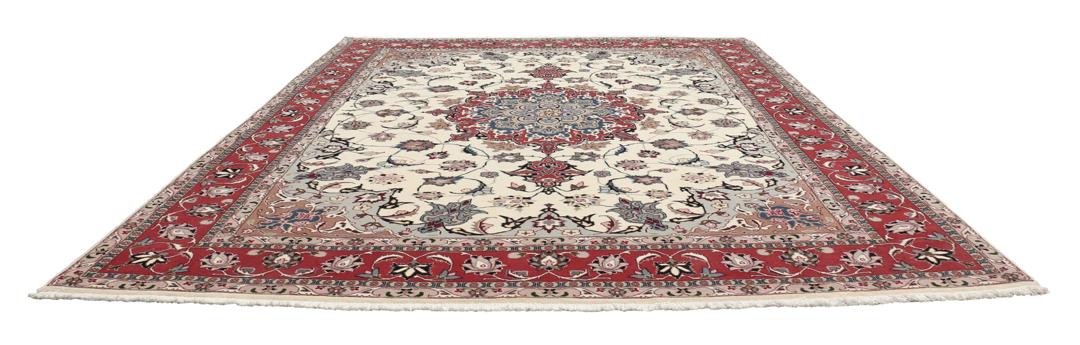 Un tapis Tabriz noué à la main provenant du Moyen-Orient avec un médaillon floral rouge sur fond crème.