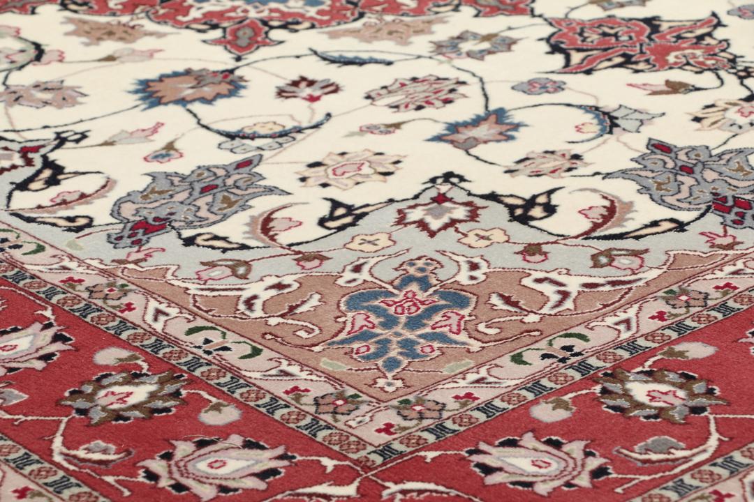 Un tapis Tabriz noué à la main provenant du Moyen-Orient avec un médaillon floral rouge sur fond crème.