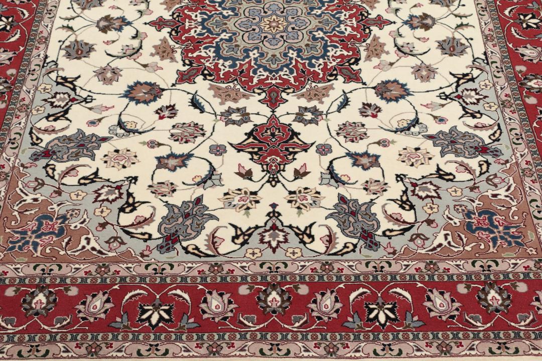 Un tapis Tabriz noué à la main provenant du Moyen-Orient avec un médaillon floral rouge sur fond crème.