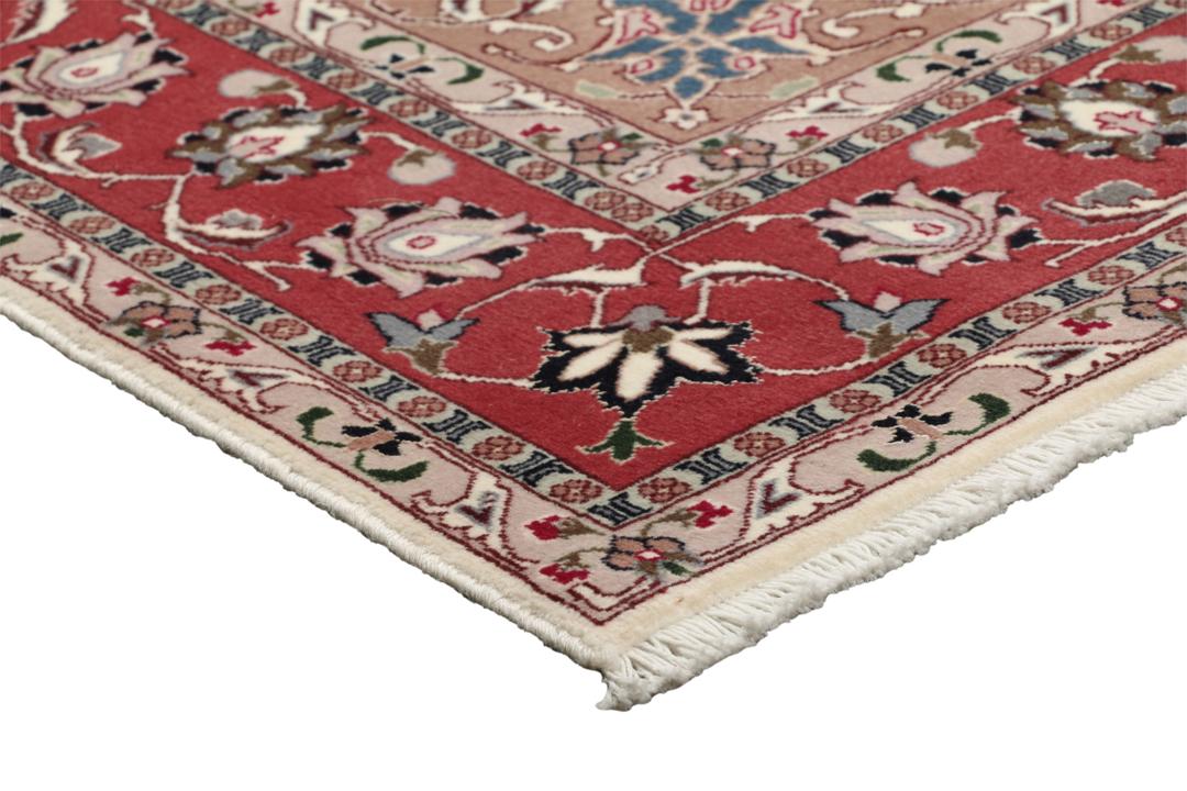 Un tapis Tabriz noué à la main provenant du Moyen-Orient avec un médaillon floral rouge sur fond crème.