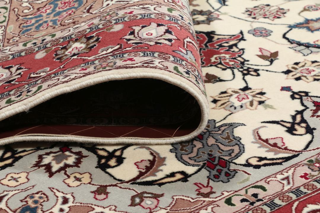 Un tapis Tabriz noué à la main provenant du Moyen-Orient avec un médaillon floral rouge sur fond crème.