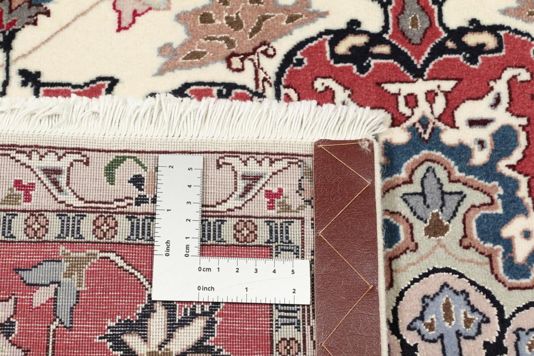 Un tapis Tabriz noué à la main provenant du Moyen-Orient avec un médaillon floral rouge sur fond crème.