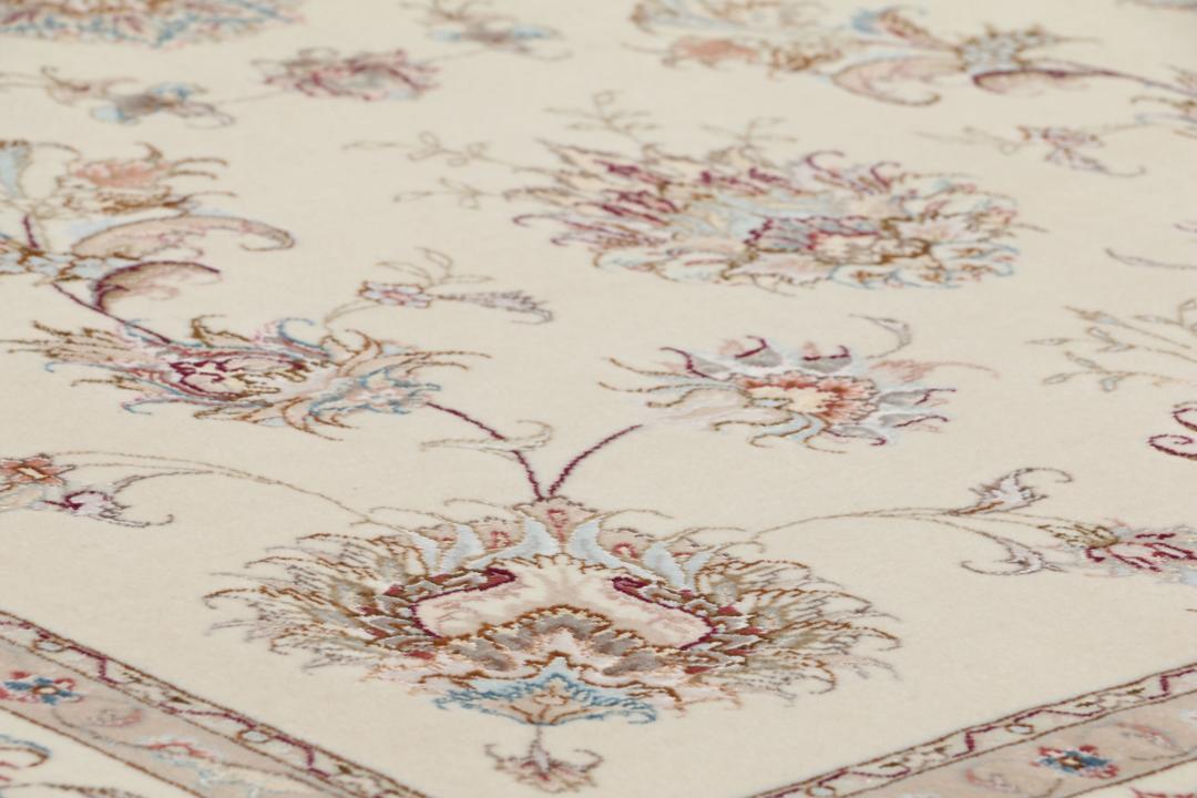 Et håndknyttet Tabriz-tæppe fra Mellemøsten i beige med indviklede blomstermønstre.