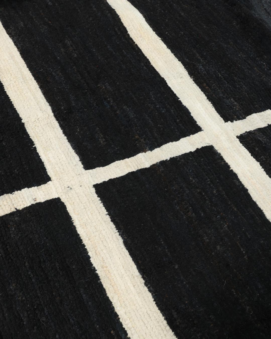 Een handgeknoopt Afghaans Gabbeh Modern vloerkleed in zwart en wit met een geometrisch vierkant patroon.