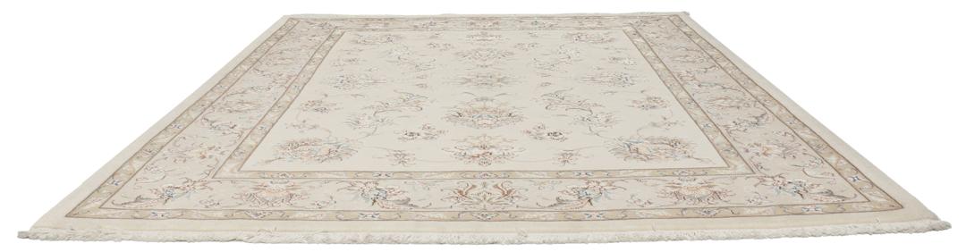 Een rechthoekig Tabriz tapijt uit het Midden-Oosten met beige tinten en bloemmotieven