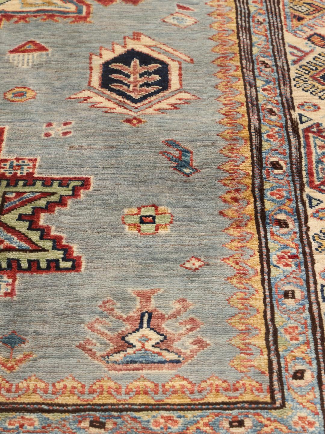 Handgeknoopt tapijt uit het Midden-Oosten met een lichtblauw veld en traditionele geometrische motieven.