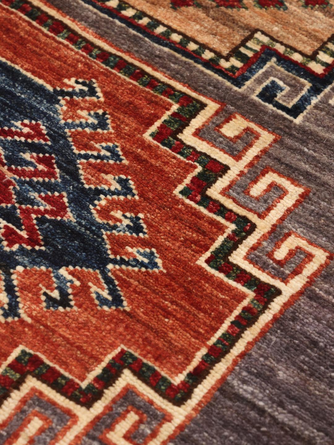 Ein rechteckiger afghanischer Kazak Ariana Teppich mit grauem Grund und farbenfrohen geometrischen Medaillons.