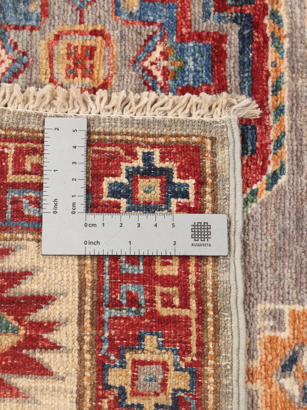 Een rechthoekig handgeknoopt Kazak tapijt uit Afghanistan met gedurfde geometrische medaillons op een grijs veld.