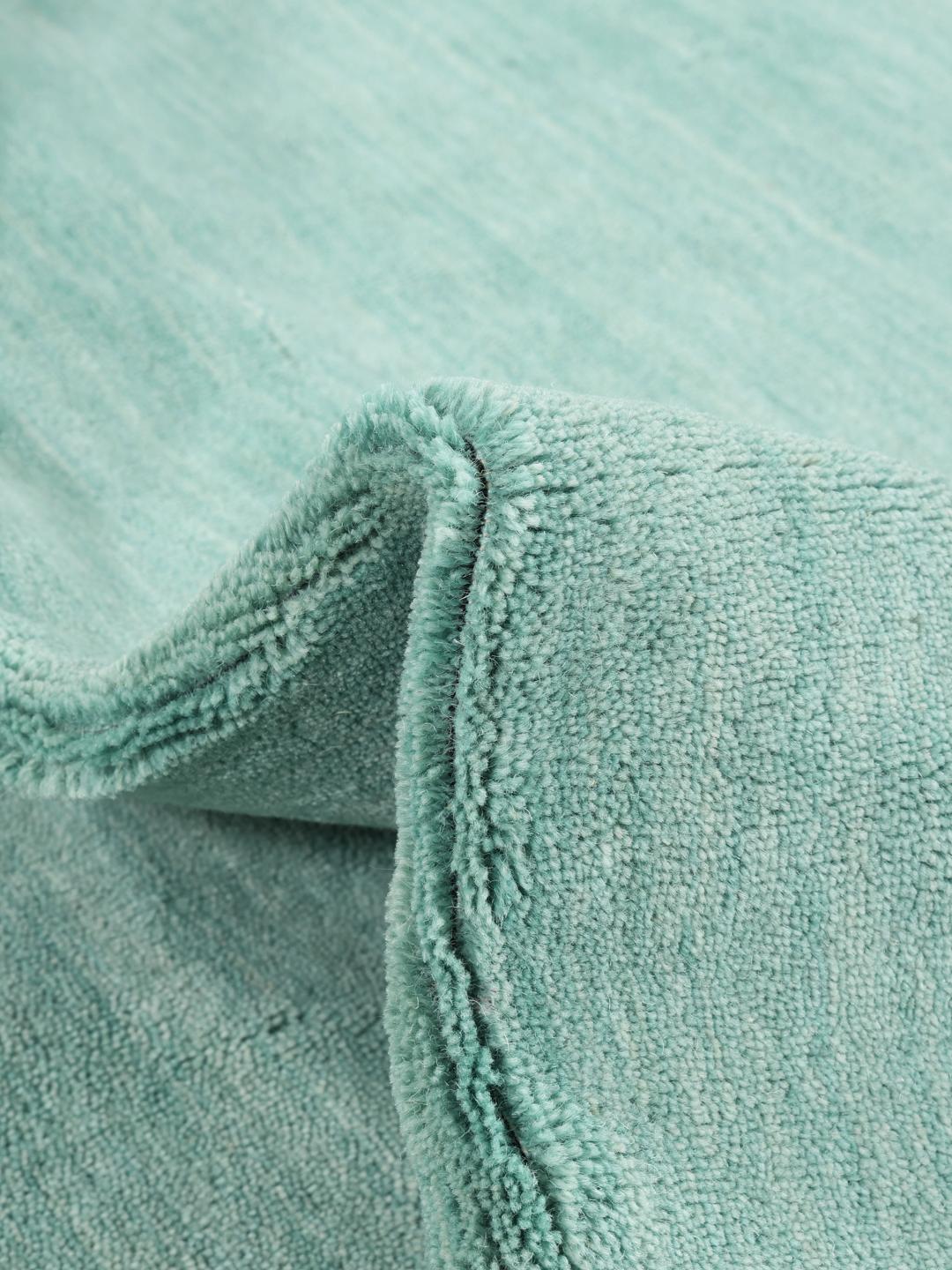 Round teal rug made from wool