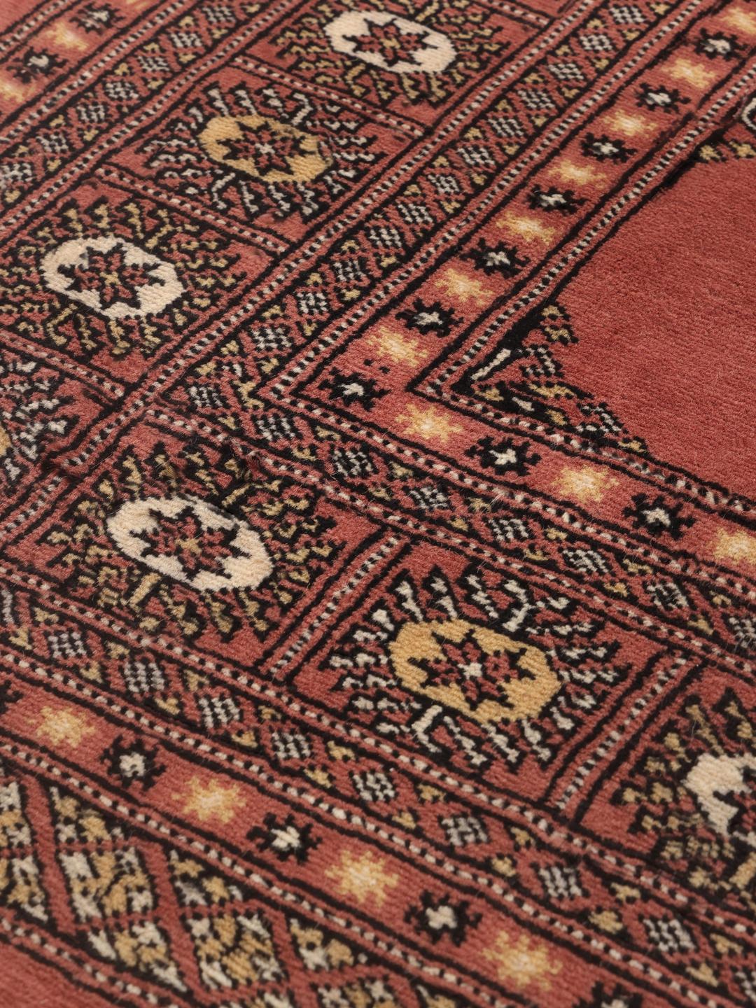 Een handgeknoopt Pakistan Bokhara 2ply vloerkleed met een rood veld en herhalende geometrische motieven.