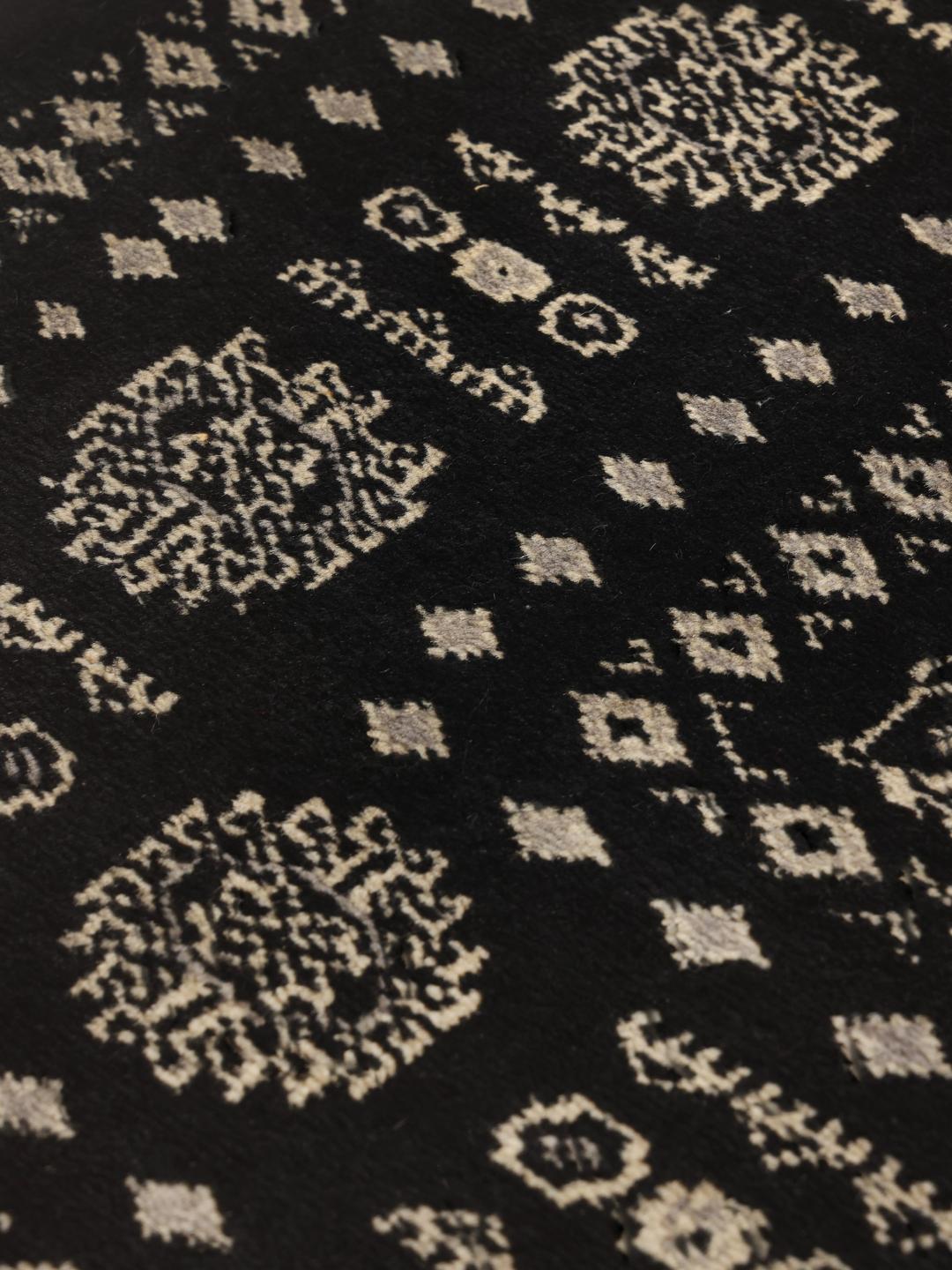 A hand-knotted Pakistan Bokhara rug in black with detailed geometric motifs.