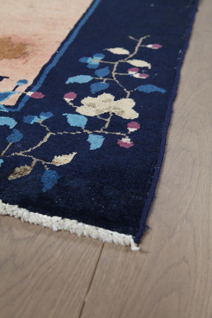 Antikt kinesisk tæppe med blomstermotiver på en beige baggrund og mørk kant