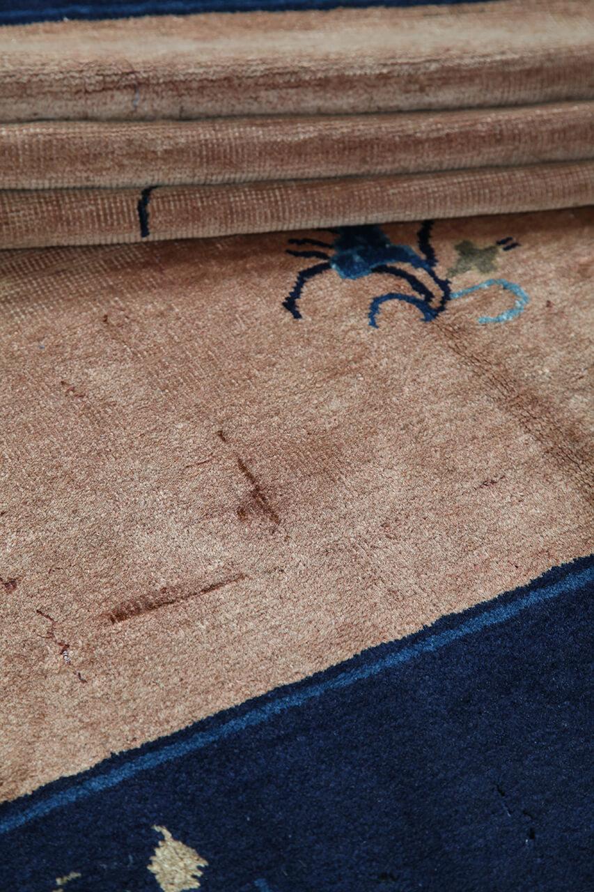 Antikt kinesisk tæppe med blomstermotiver på en beige baggrund og mørk kant