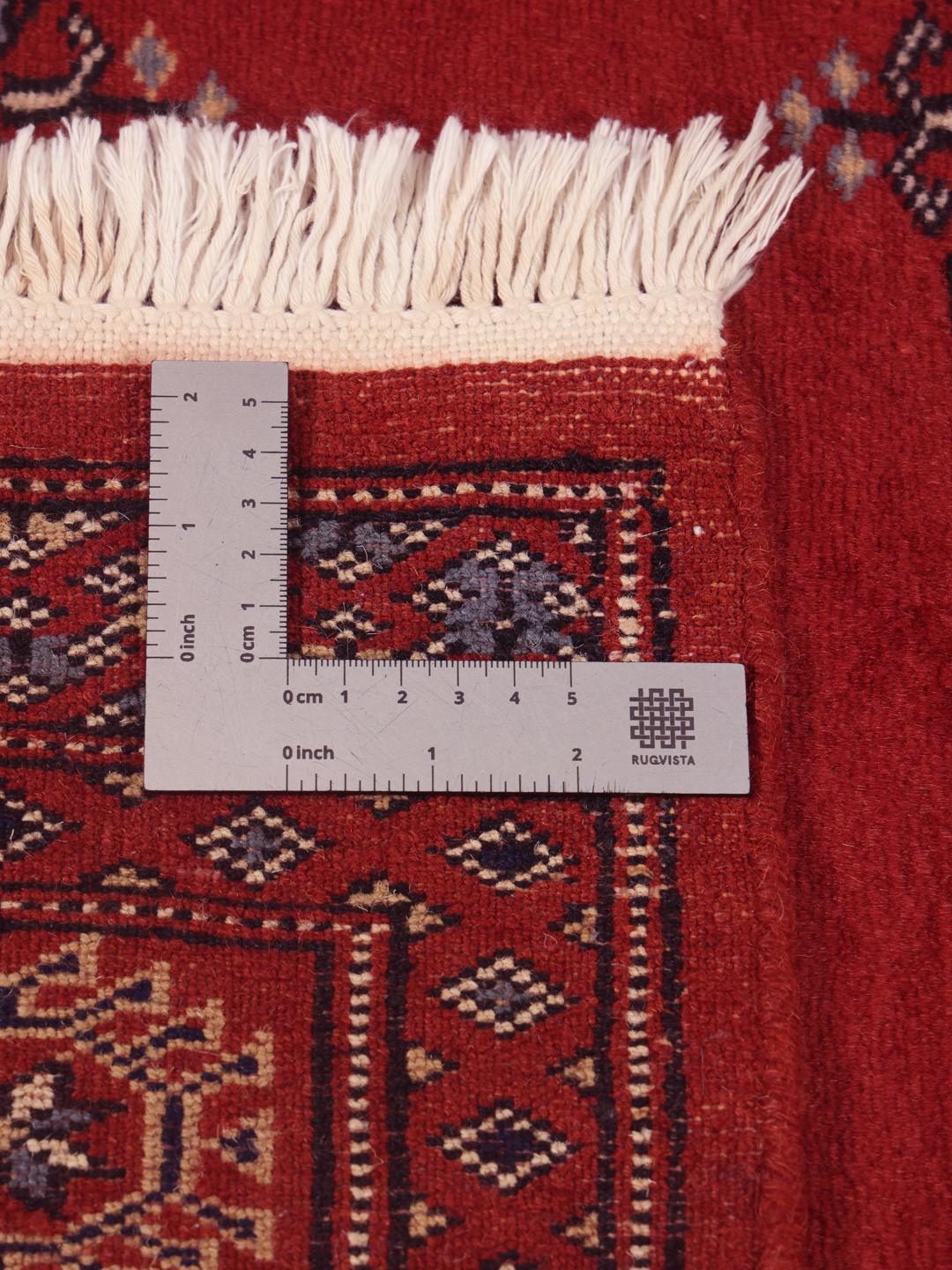 Hand-knotted Pakistan Bokhara rug in a deep red color with traditional motifs.
