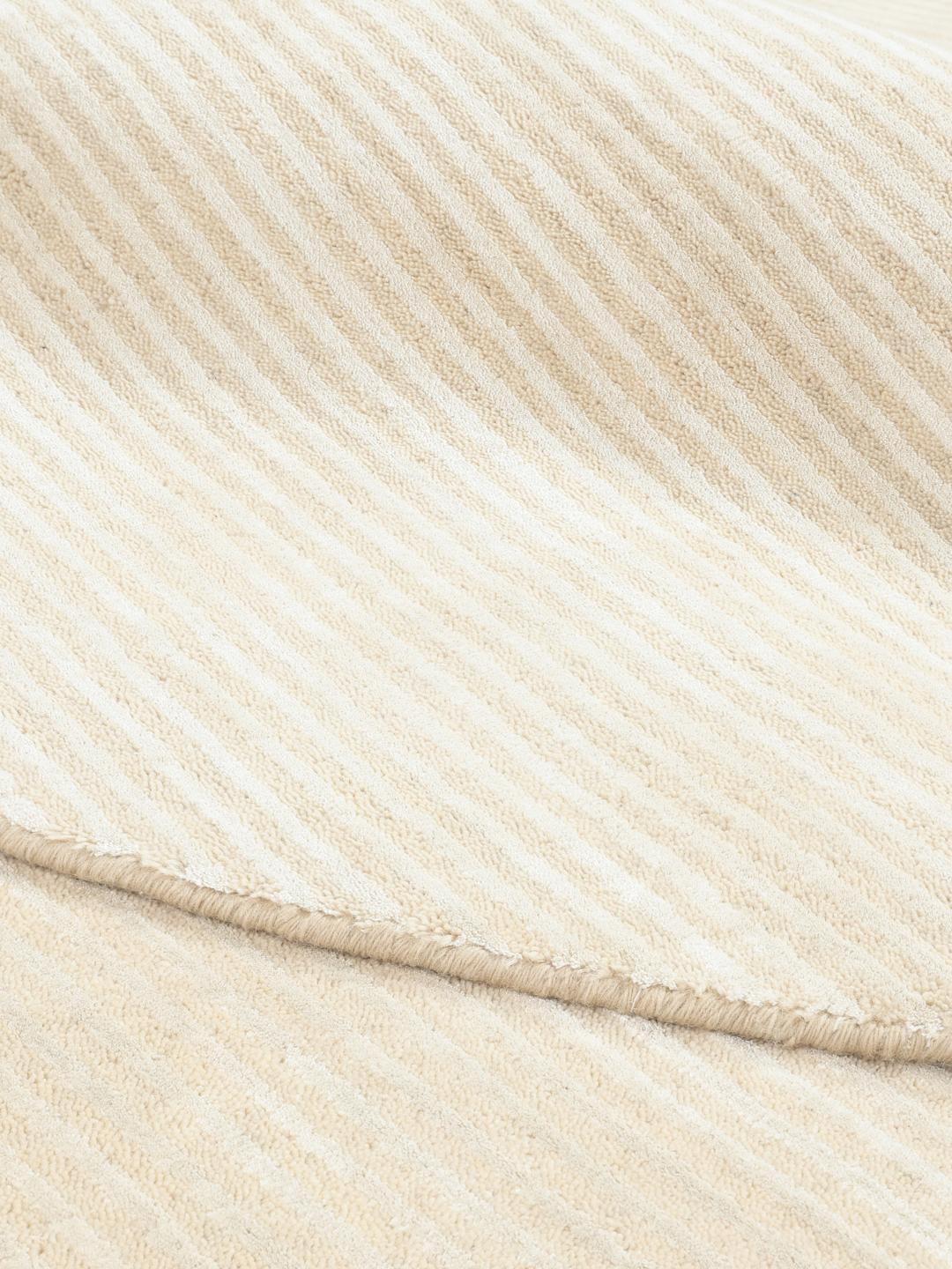 Un tapis rond beige avec un motif à fines rayures