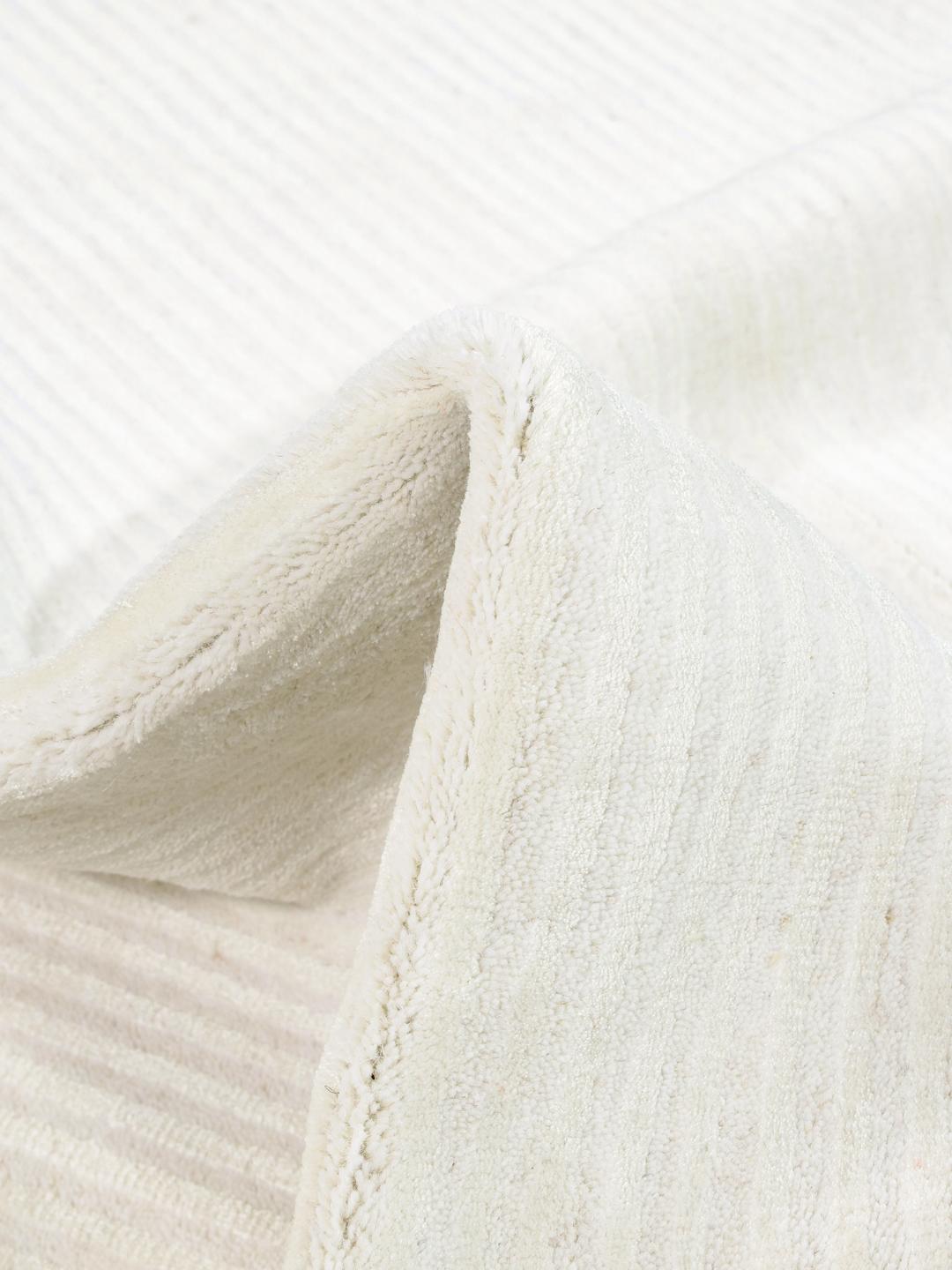 Un tapis en laine blanche avec une texture à fines rayures.