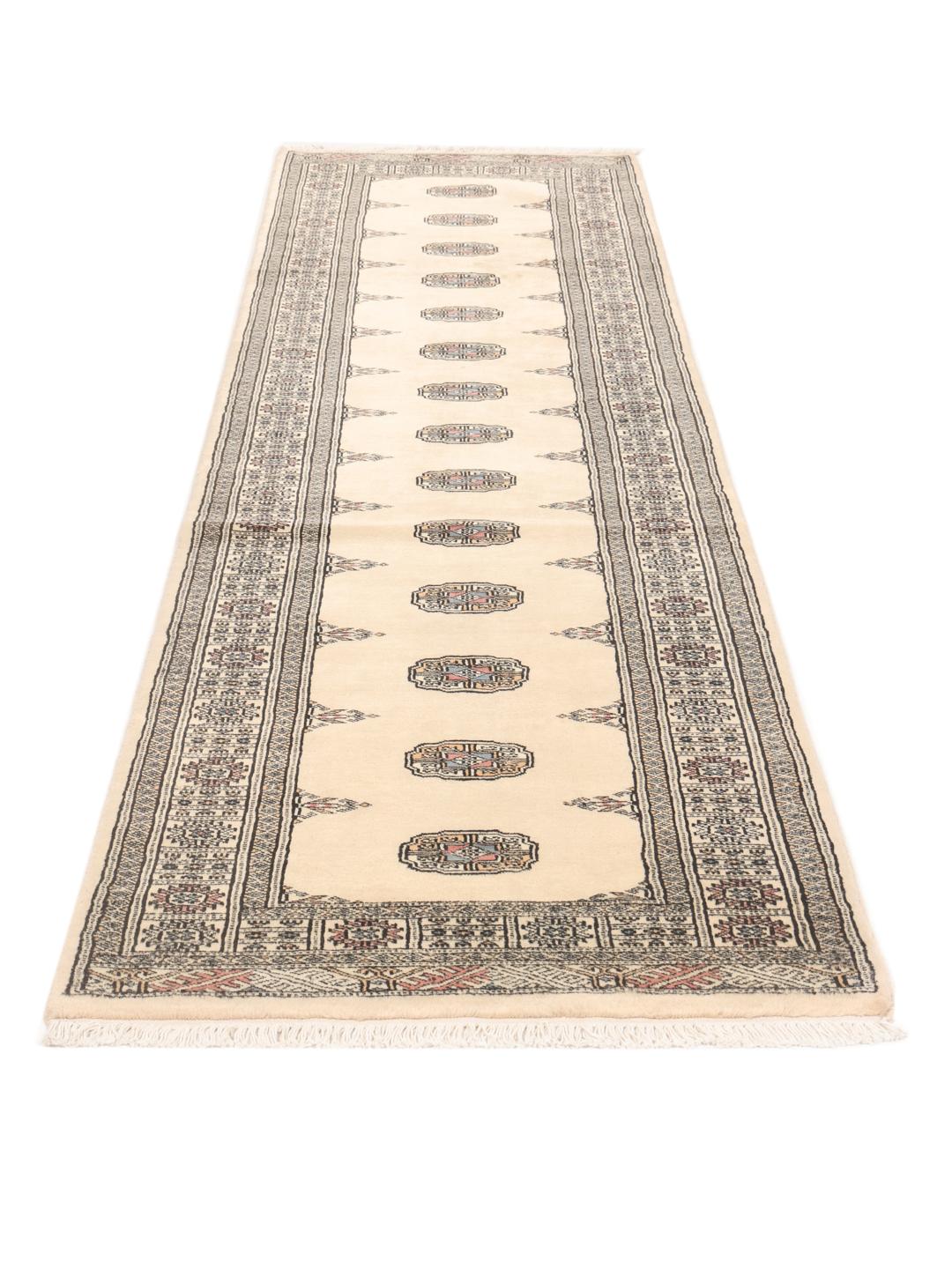 A hand-knotted beige runner from Pakistan with traditional patterns.
