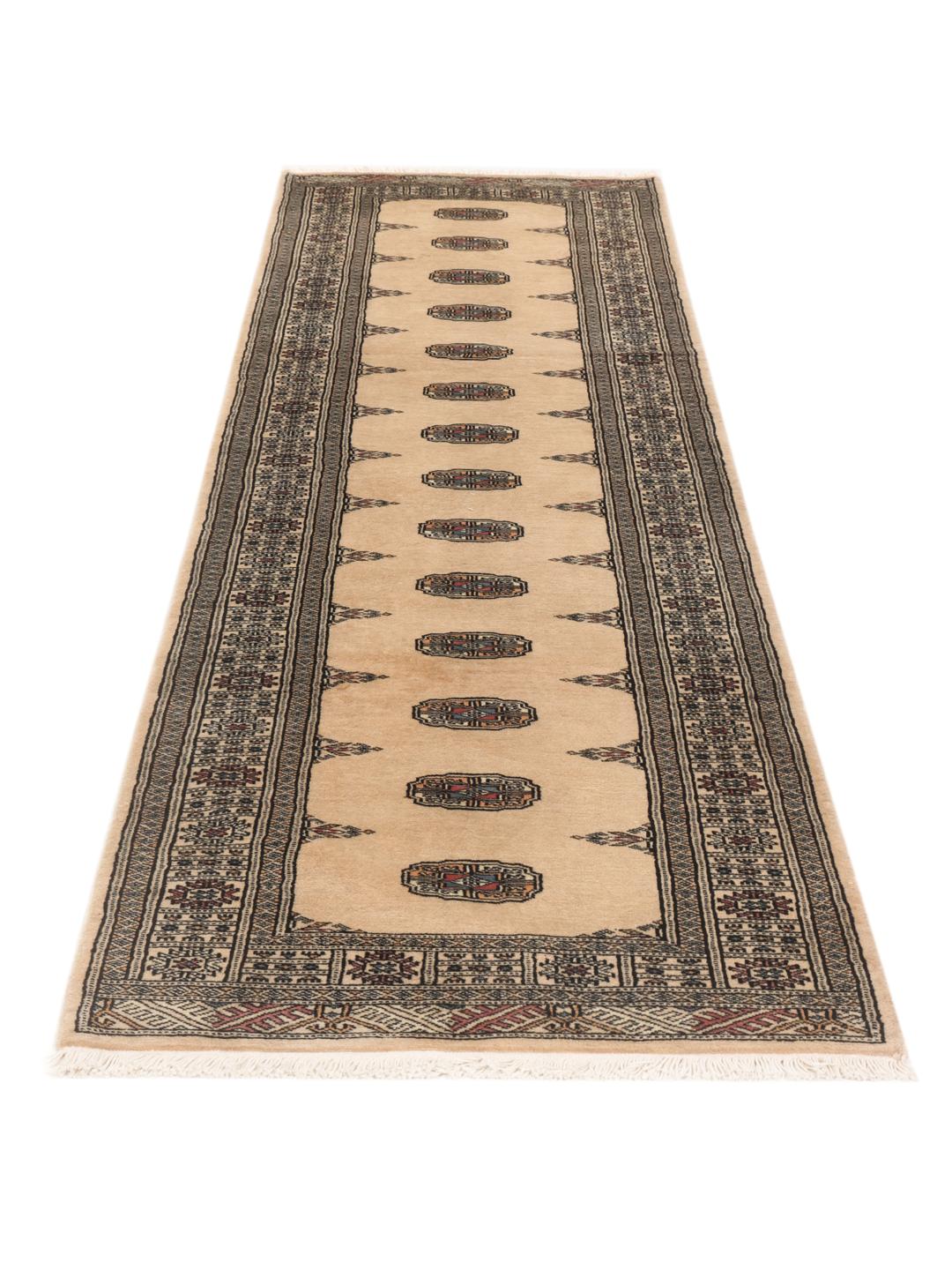 A hand-knotted beige runner from Pakistan with traditional patterns.