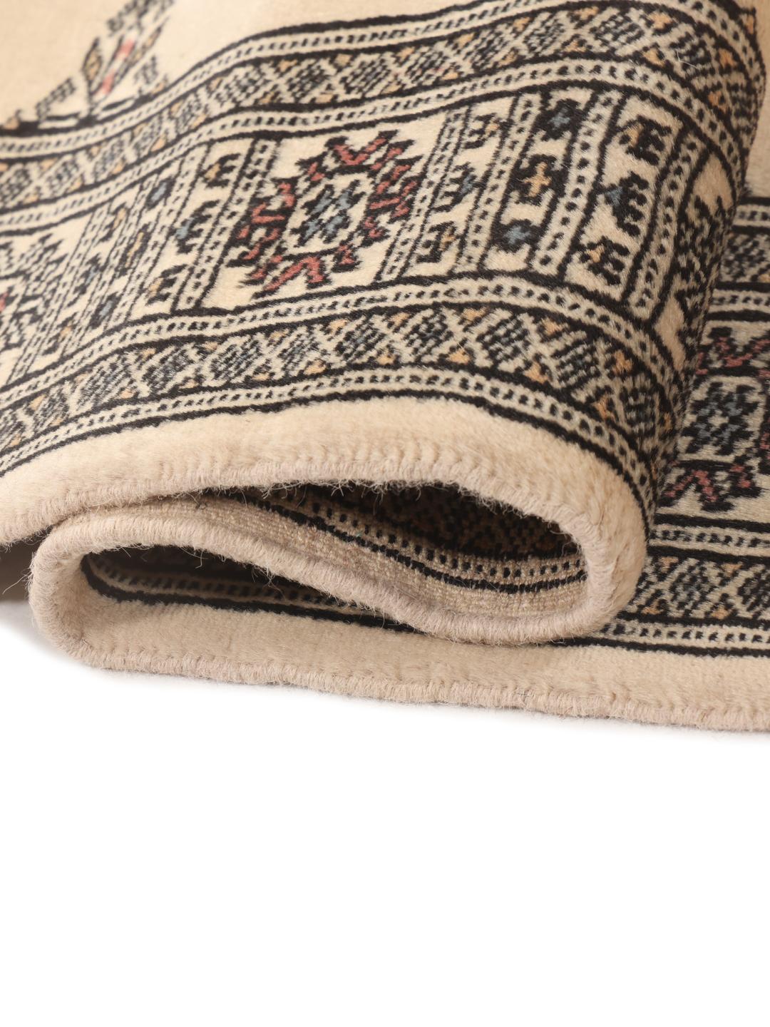 A hand-knotted beige runner from Pakistan with traditional patterns.