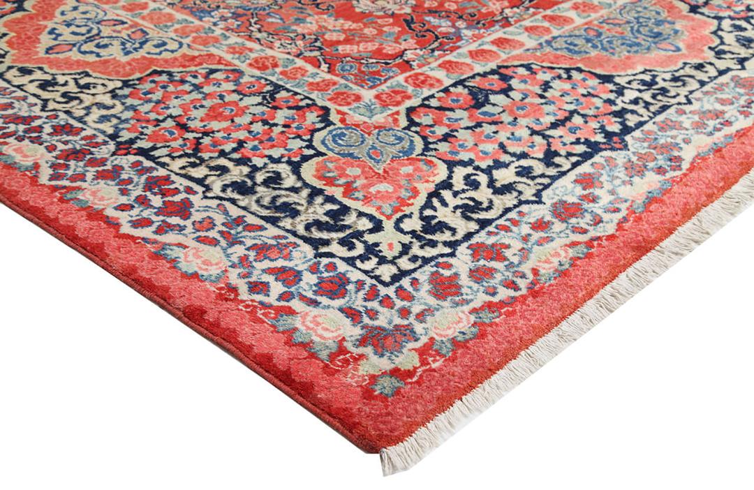 A large rectangular antique Sarouk rug from the Middle East featuring a vibrant red and dark-blue floral pattern