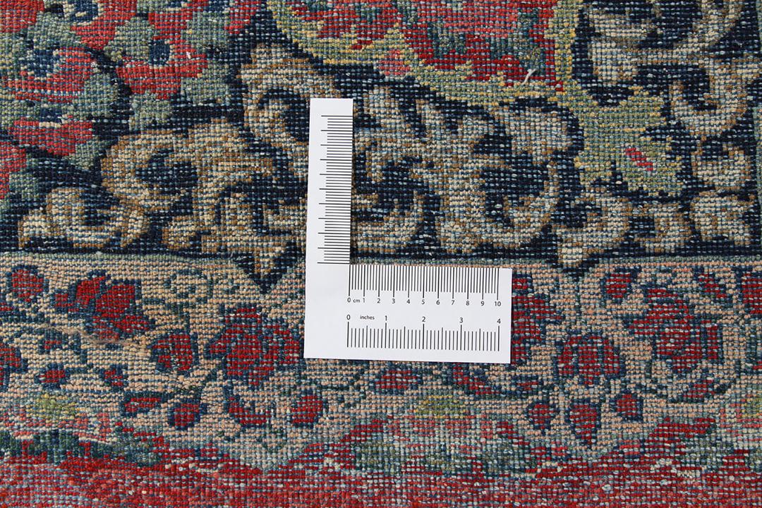 A large rectangular antique Sarouk rug from the Middle East featuring a vibrant red and dark-blue floral pattern