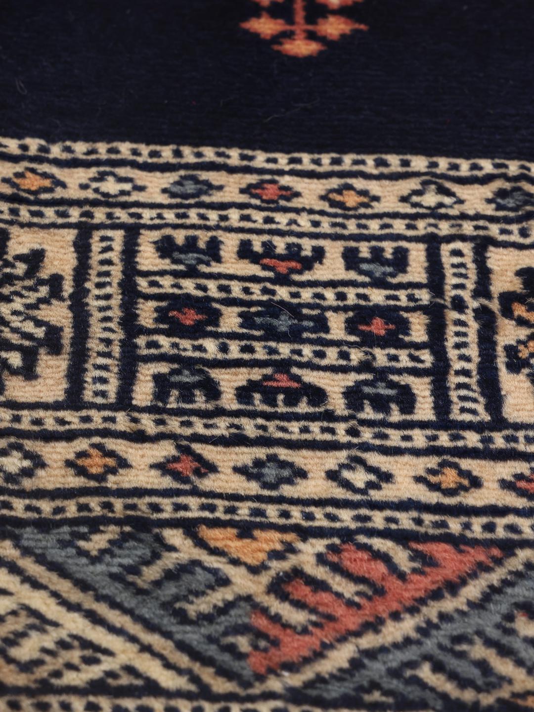 A long, narrow hand-knotted runner from Pakistan with a deep blue field and repeating motifs.