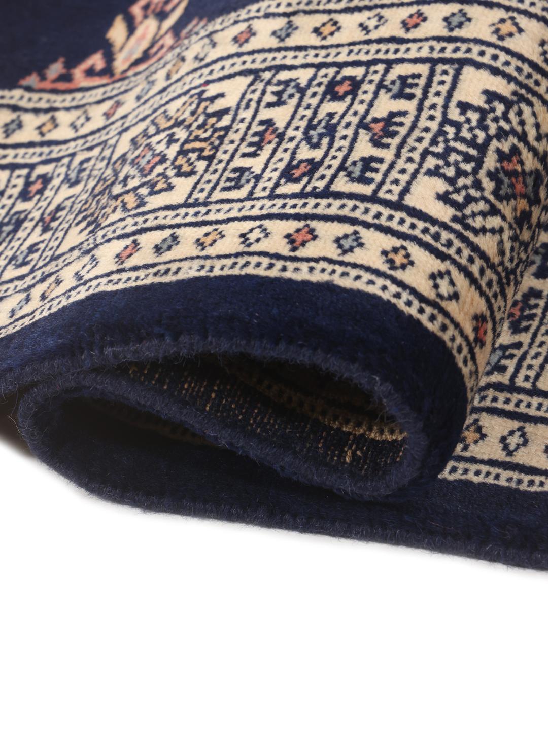 A long, narrow hand-knotted runner from Pakistan with a deep blue field and repeating motifs.