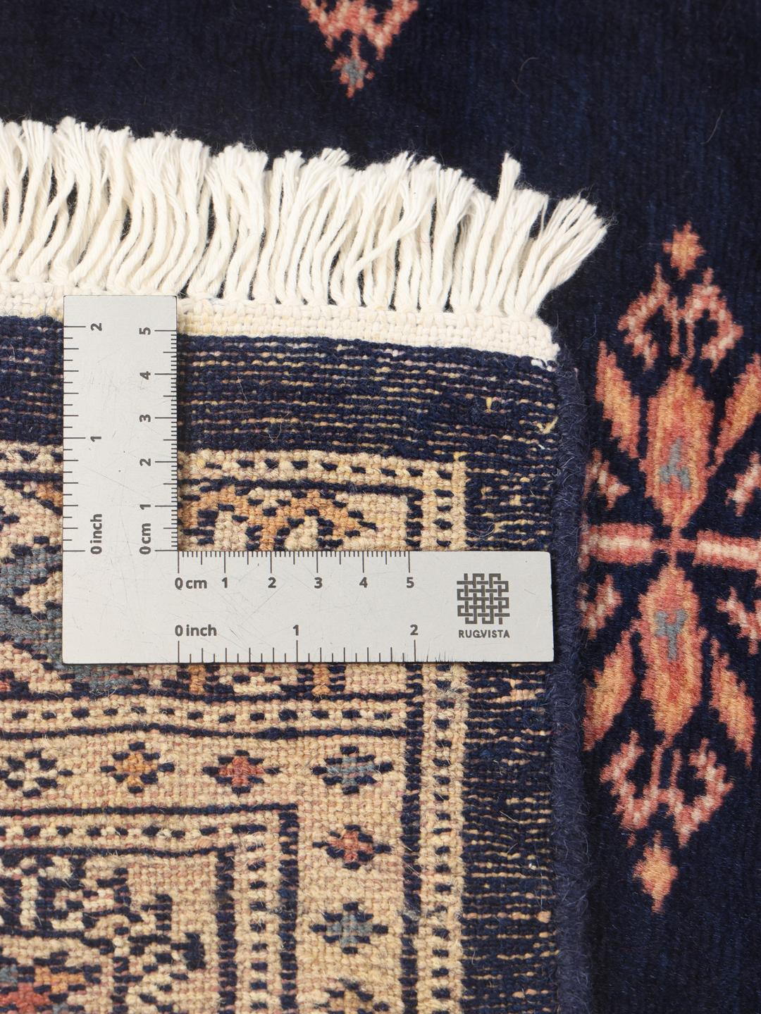 A long, narrow hand-knotted runner from Pakistan with a deep blue field and repeating motifs.