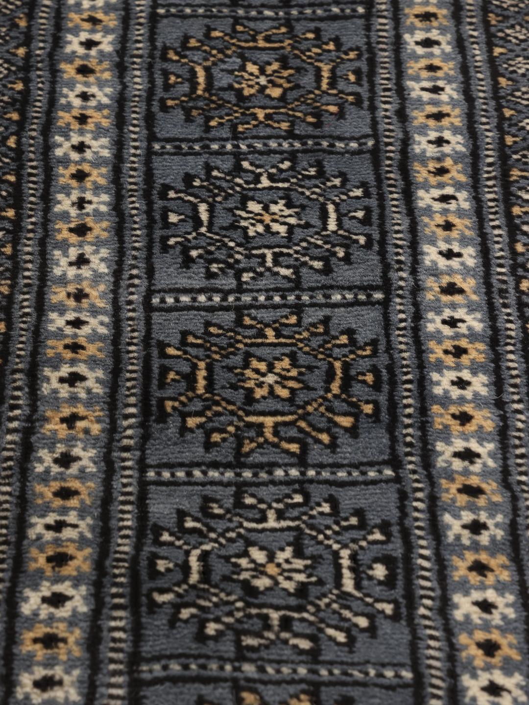 A hand-knotted Pakistan Bokhara rug with a blue field and repeating motifs.