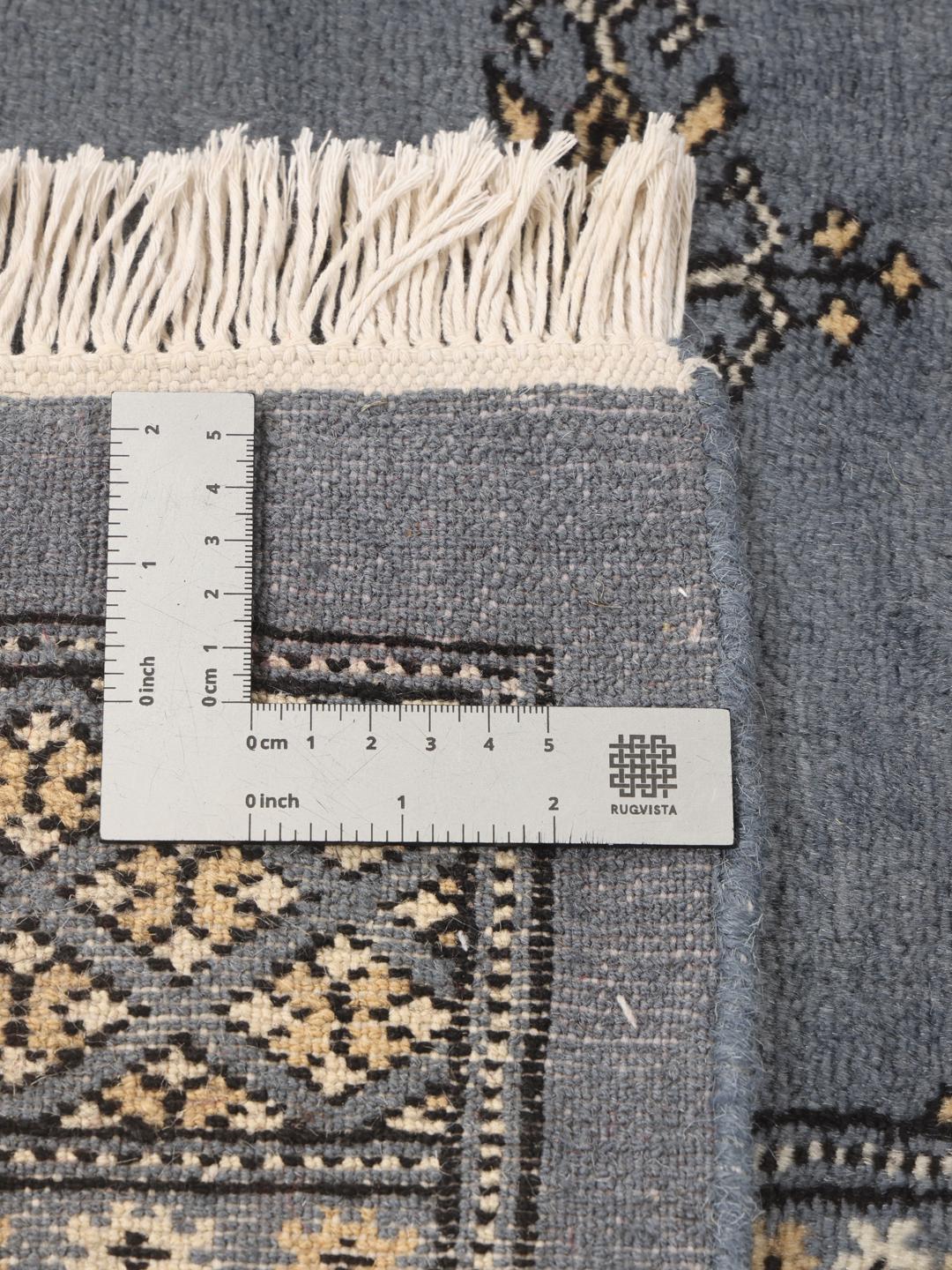 A hand-knotted Pakistan Bokhara rug with a blue field and repeating motifs.