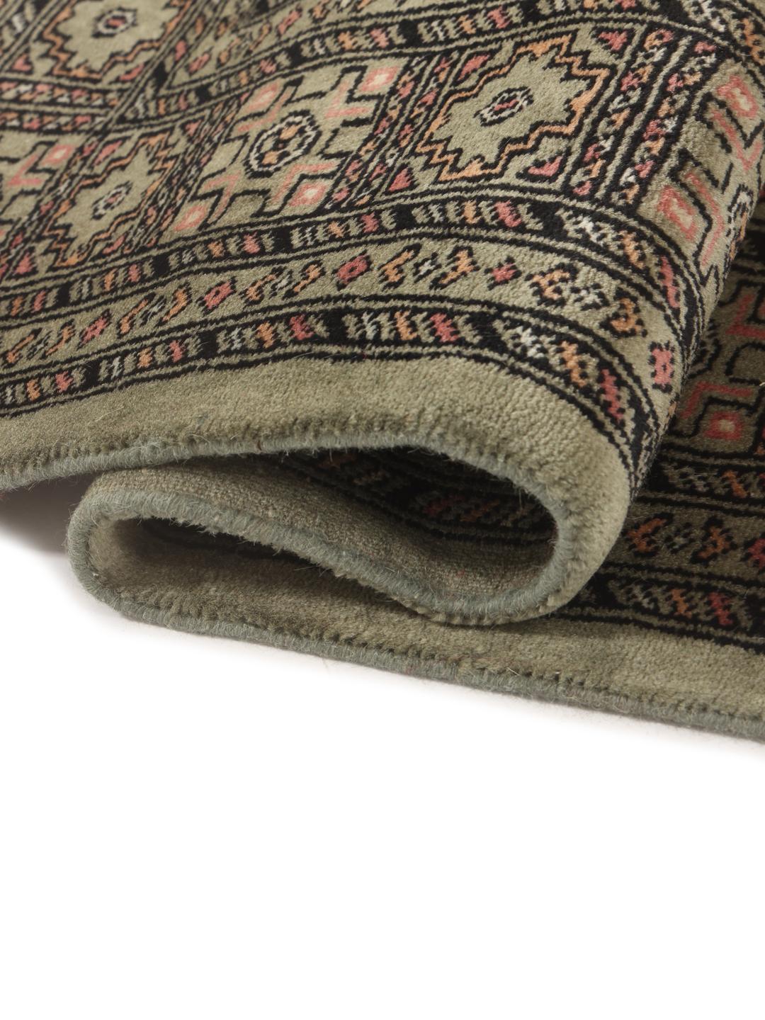 A hand-knotted Pakistan Bokhara 3ply rug with a green field and traditional motifs.