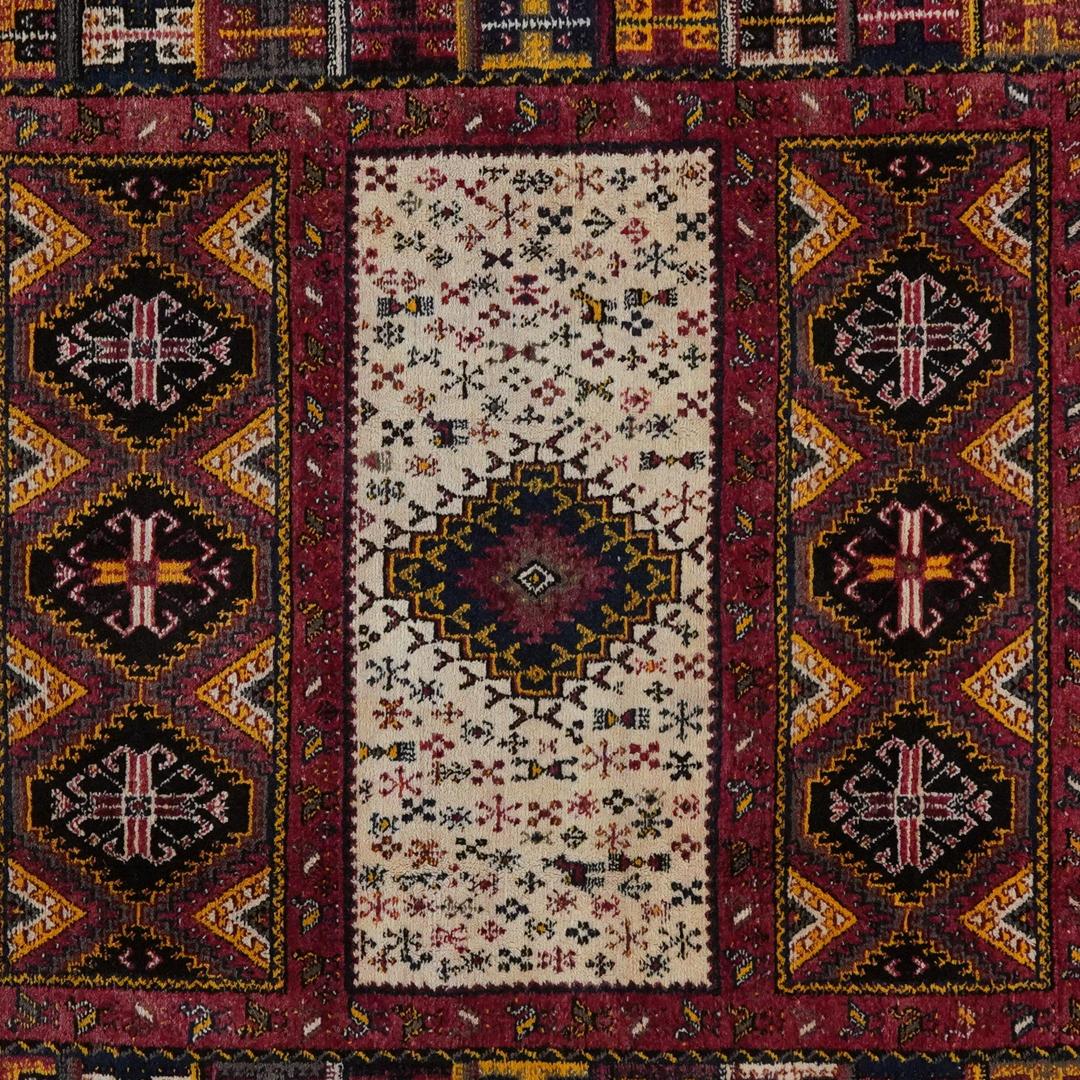 Handgefertigter Vintage-Teppich aus marokkanischer Wolle mit geometrischen Stammesmotiven in Rot, Blau und Creme.