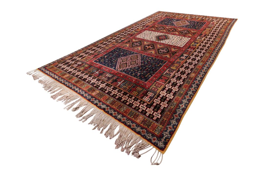 Handgefertigter Vintage-Teppich aus marokkanischer Wolle mit geometrischen Stammesmotiven in Rot, Blau und Creme.